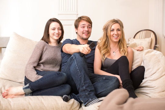 Three teenage friends sitting watching television
