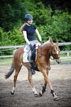 Young girl riding her brown horse outdoors and smiling
