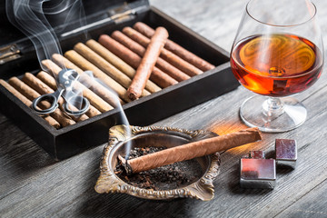 Aroma floating up from cigar and cognac in glass - obrazy, fototapety, plakaty