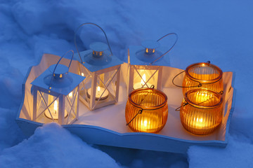 Beautiful lanterns on wooden tray. Snow around