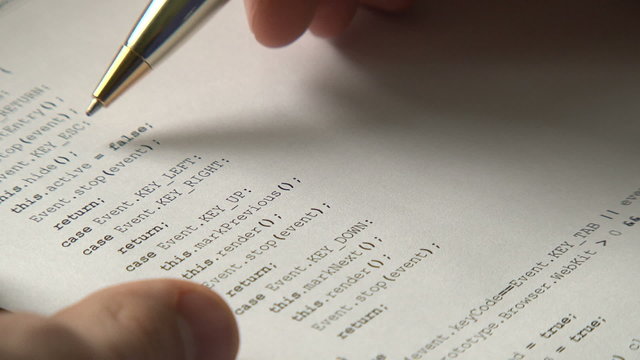 Young computer programmer verifying code on paper
