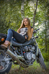 girl posing on a motorcycle on the background of nature