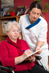 Krankenschwester hilt Seniorin bei einem Formular