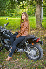 girl posing on a motorcycle on the background of nature