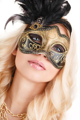 Beautiful young woman in mysterious golden Venetian mask.