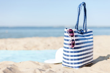 straw hat, sunglasses and bag lying in the sand