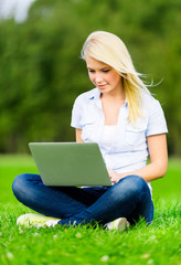 Attractive female student with silver laptop in summer park