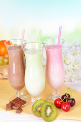 Milk shakes with fruits on table on light blue background