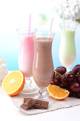 Milk shakes with fruits on table on light blue background