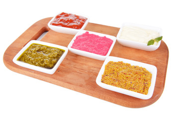Various sauces on chopping board isolated on white