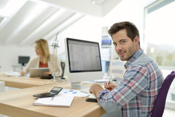 Fototapeta na wymiar Smiling office worker sitting at desk
