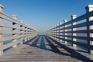White pier on the beach with blue sky