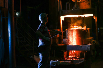A founder holding a crucible of molten cast iron
