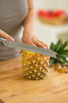 Closeup on young woman cutting pineapple