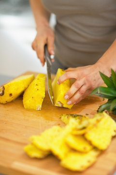 Closeup on young woman cutting pineapple