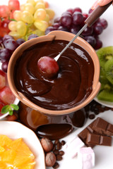 Chocolate fondue with sliced fruits, isolated on white
