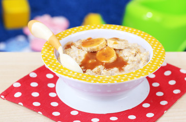 Bowl of porridge for baby and toys  on table, on toys