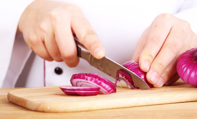 Obraz na płótnie Canvas Female hands cutting bulb onion, close up