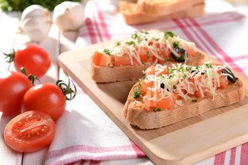 Delicious bruschetta with tomatoes on cutting board close-up