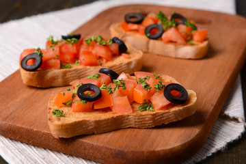 Delicious bruschetta with tomatoes on cutting board close-up