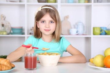 Obraz na płótnie Canvas Beautiful little girl eating breakfast in kitchen at home