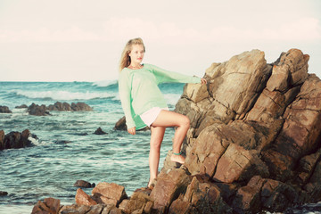 Blonde lady standing on rocks in the ocean
