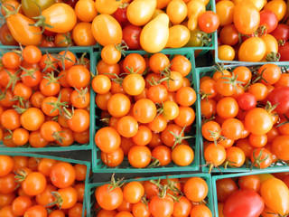 Close up of orange cherry tomatoes in green plastic baskets