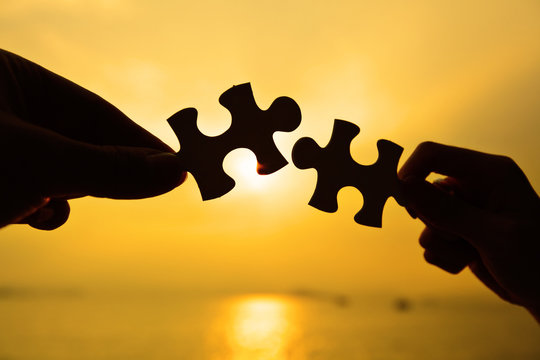 Silhouette of two hands connect jigsaw together
