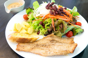 Fish steak with salad, dipping sauce and garlic bread