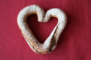 Herzförmiges Brot auf bordeauxfarbenem Tuch