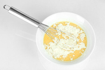 Corolla and broken eggs with flour isolated on white