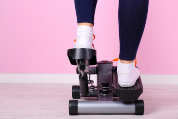 Woman doing exercise on stepper. Close-up on legs.