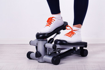 Woman doing exercise on stepper. Close-up on legs.