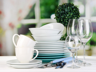 Clean dishes on table on window background