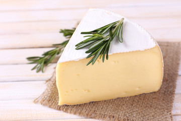 Tasty Camembert cheese with rosemary, on wooden table