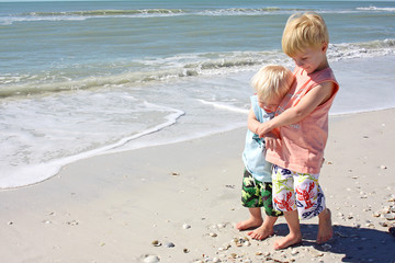 Young Children Hugging as They Walk Along the Beach Shore 