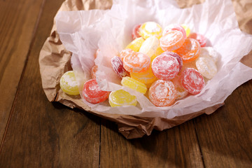 Sweet  multicolor candies on paper, on wooden background