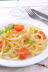 Delicious spaghetti with tomatoes on plate on table close-up