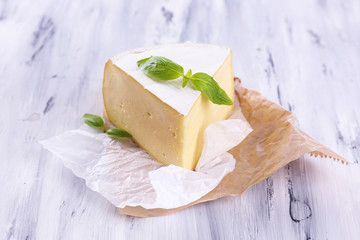 Tasty Camembert cheese with basil, on wooden table