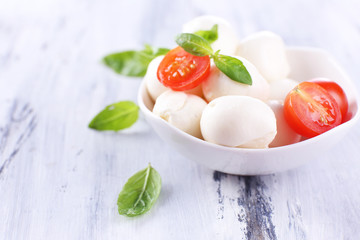 Tasty mozzarella cheese with basil and tomatoes in bowl,