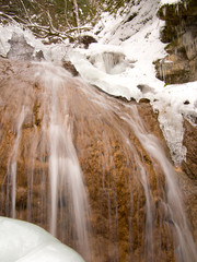 Water flows slowly over the rocks on the background of icicles