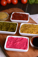 Various sauces on chopping board on table close-up