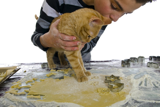 Junge sticht Pl&auml;tzchen aus uns seine Katze hilft mit