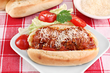 Meatball parmesan sub sandwich with side salad.