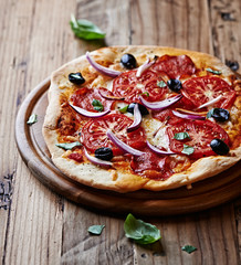 Pizza with salami, tomatoes and red onion