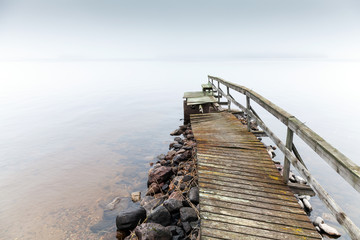 Old ruined wooden pier. Saimaa lake in foggy morning