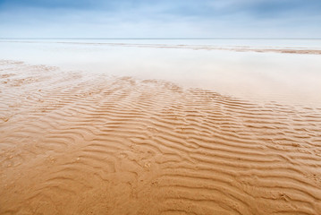 Fototapeta na wymiar Waves on empty sandy coast of Baltic Sea