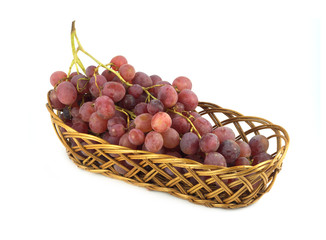 Red grape on branch in brown wicker basket isolated