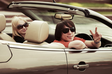 Happy young couple driving convertible car