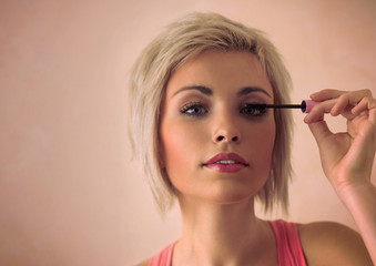 Obraz na płótnie Canvas Elegant blonde beauty doing makeup